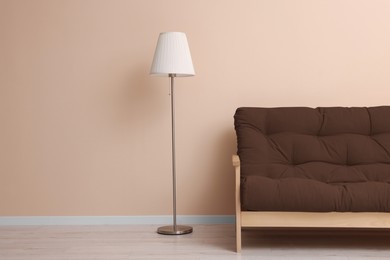 Image of Sofa in mocha mousse shade and floor lamp near beige wall indoors. Interior with trendy color of 2025 year