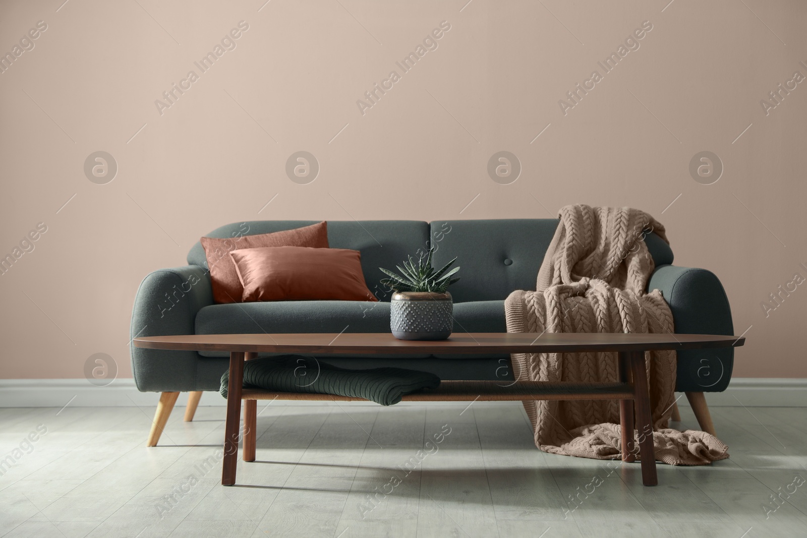 Image of Grey sofa with pillows in mocha mousse shade and table indoors. Trendy color of 2025 year in interior design