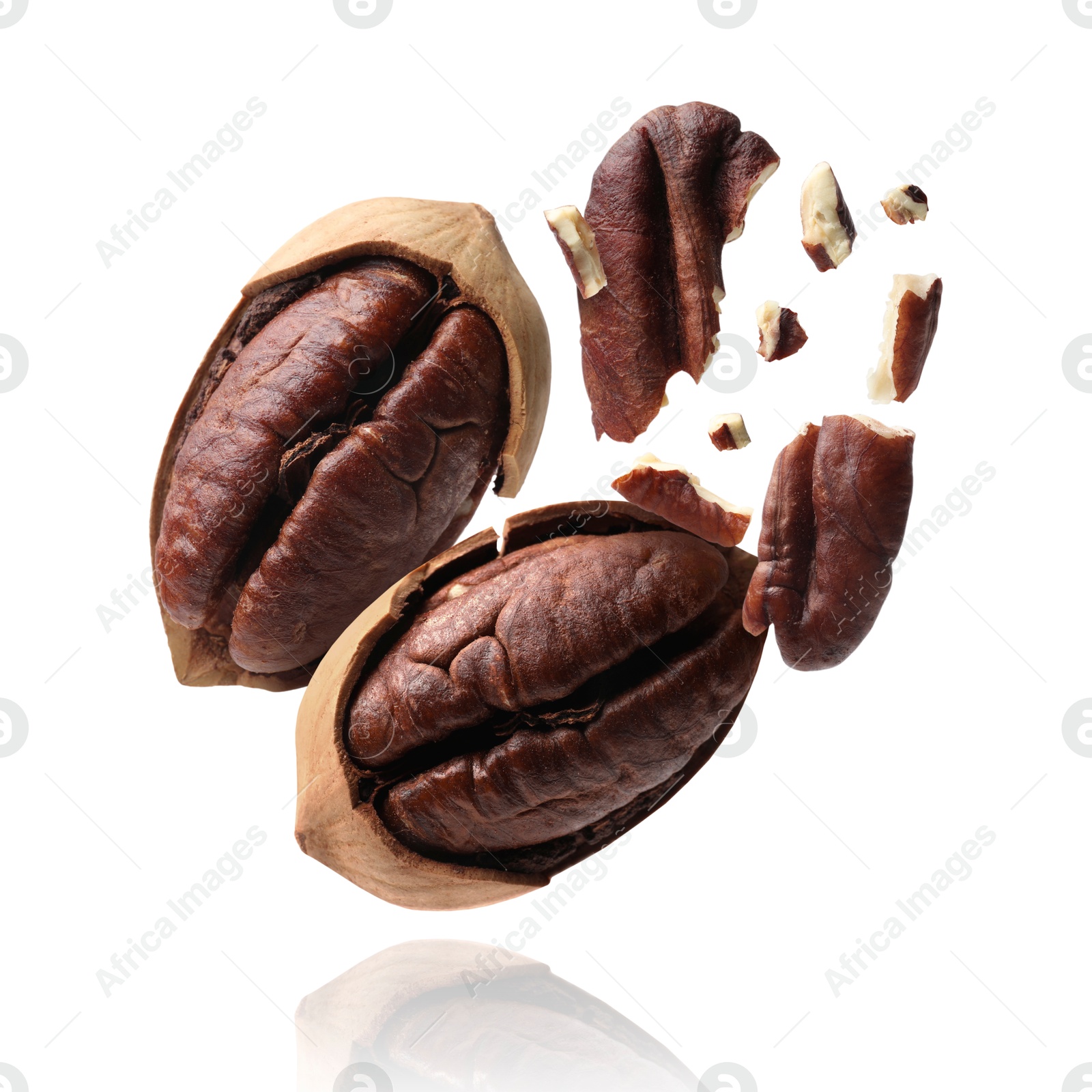 Image of Broken pecan nuts in air on white background