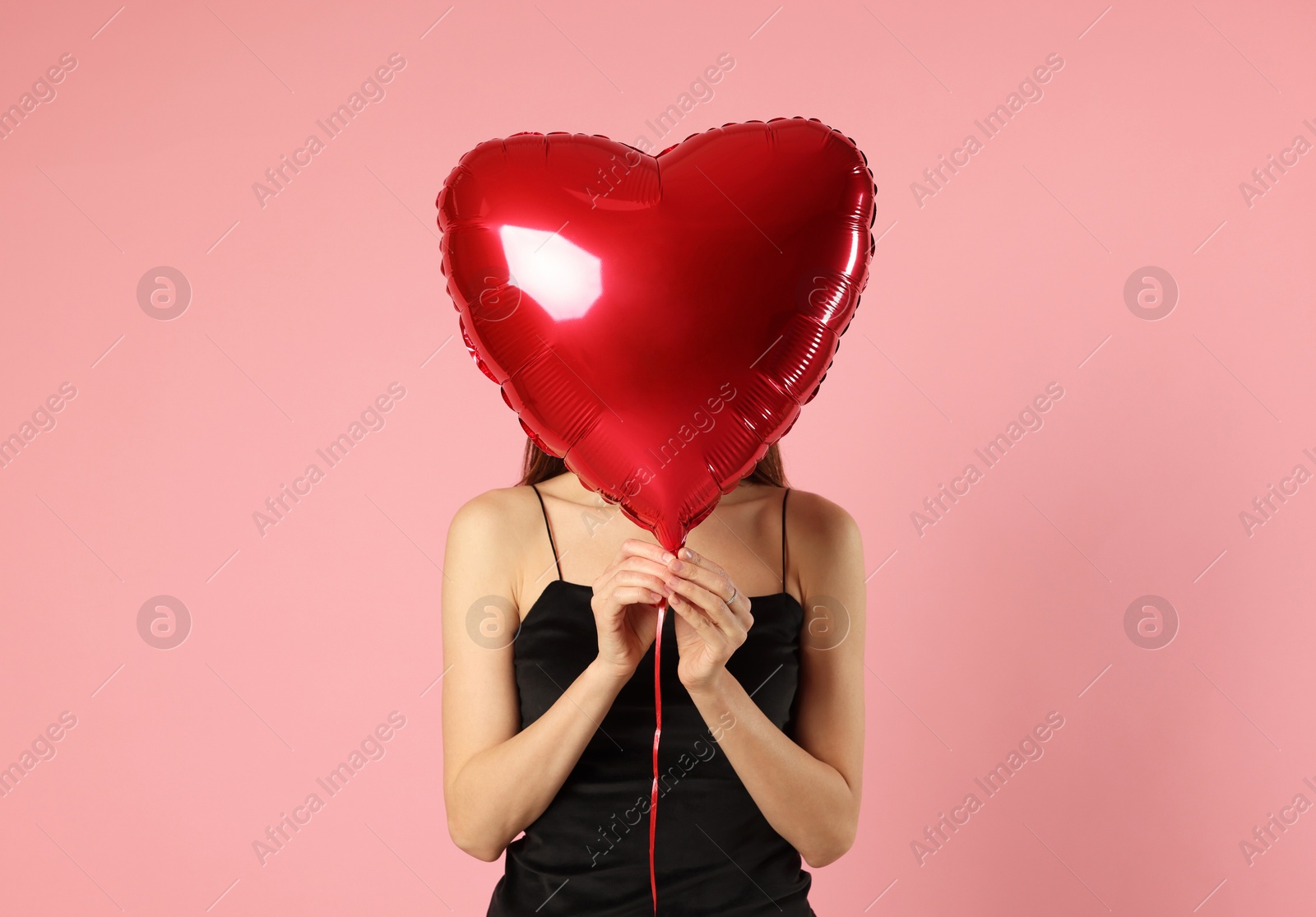 Photo of Happy Valentine's Day. Woman with heart shaped balloon on pink background