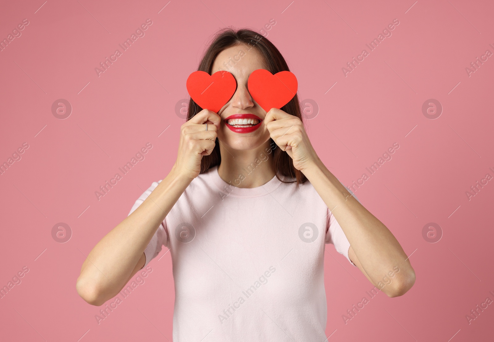 Photo of Happy Valentine's Day. Woman covering her face with paper hearts on pink background