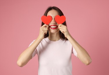 Photo of Happy Valentine's Day. Woman covering her face with paper hearts on pink background