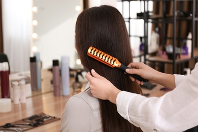 Photo of Stylist working with client in salon, making hairstyle