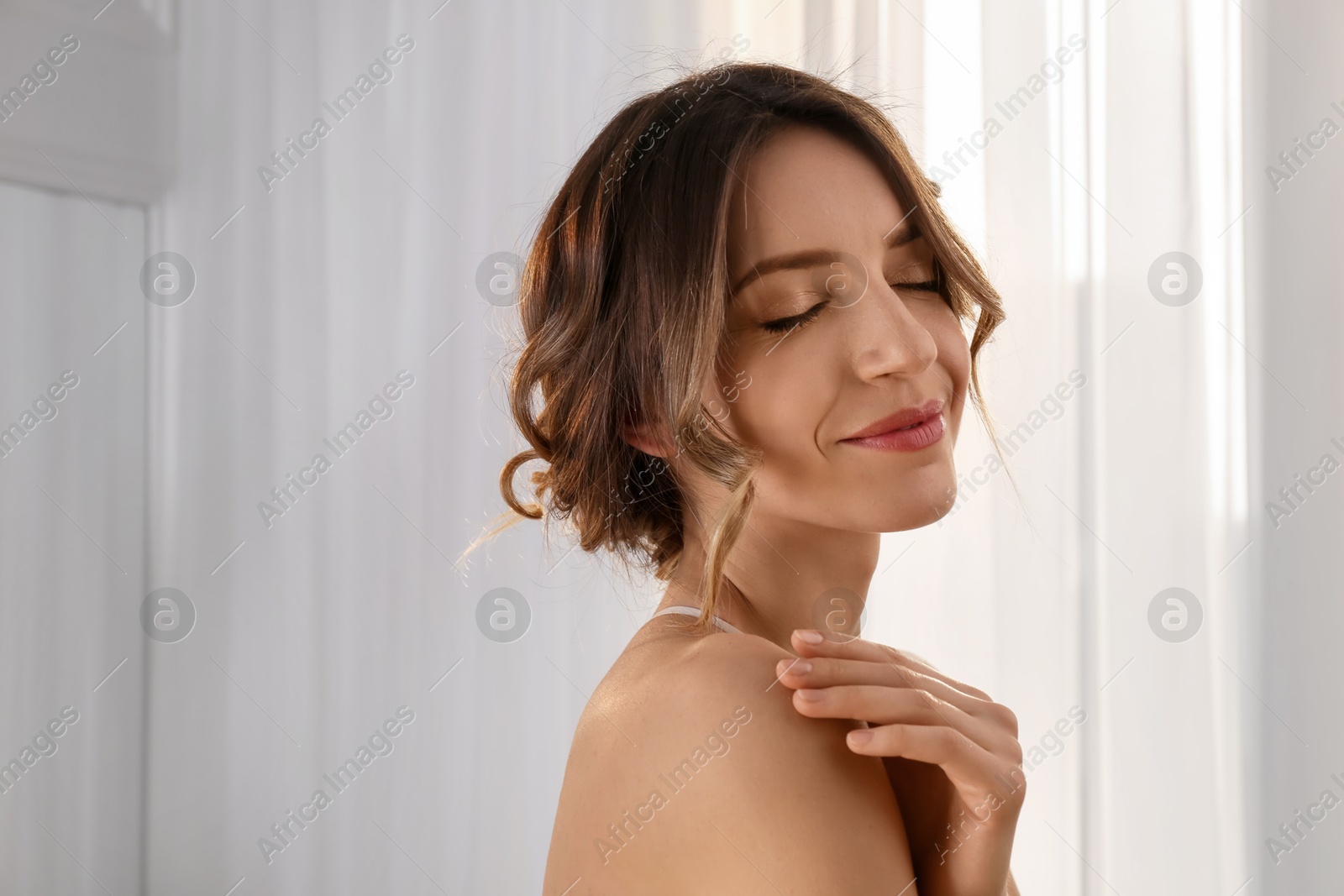 Photo of Young woman with beautiful hairstyle near window indoors. Space for text