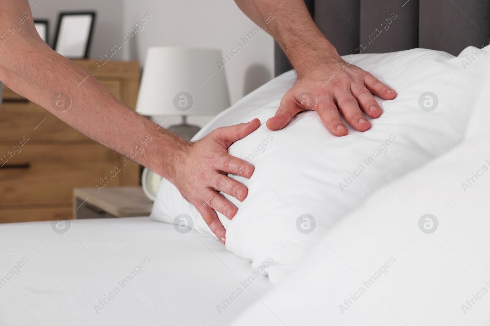 Photo of Man adjusting pillow on bed at home, closeup