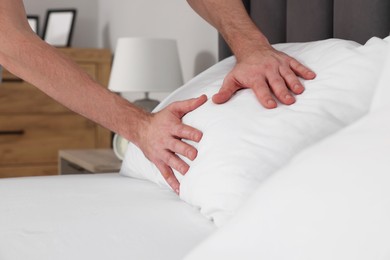 Photo of Man adjusting pillow on bed at home, closeup