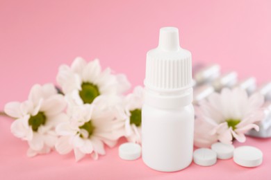 Photo of Allergy treatment. Nasal drops, pills and flowers on pink background, closeup