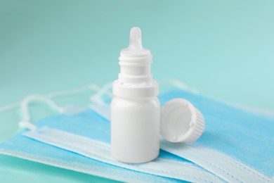 Photo of Allergy treatment. Nasal drops and protective masks on light blue background, closeup