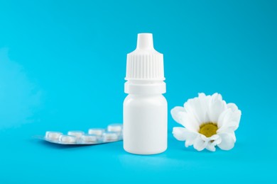 Photo of Allergy treatment. Nasal drops, pills and flower on light blue background, closeup