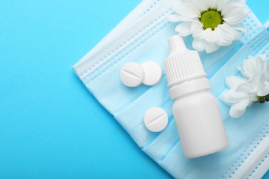 Photo of Allergy treatment. Nasal drops, pills, flowers and protective mask on light blue background, flat lay. Space for text