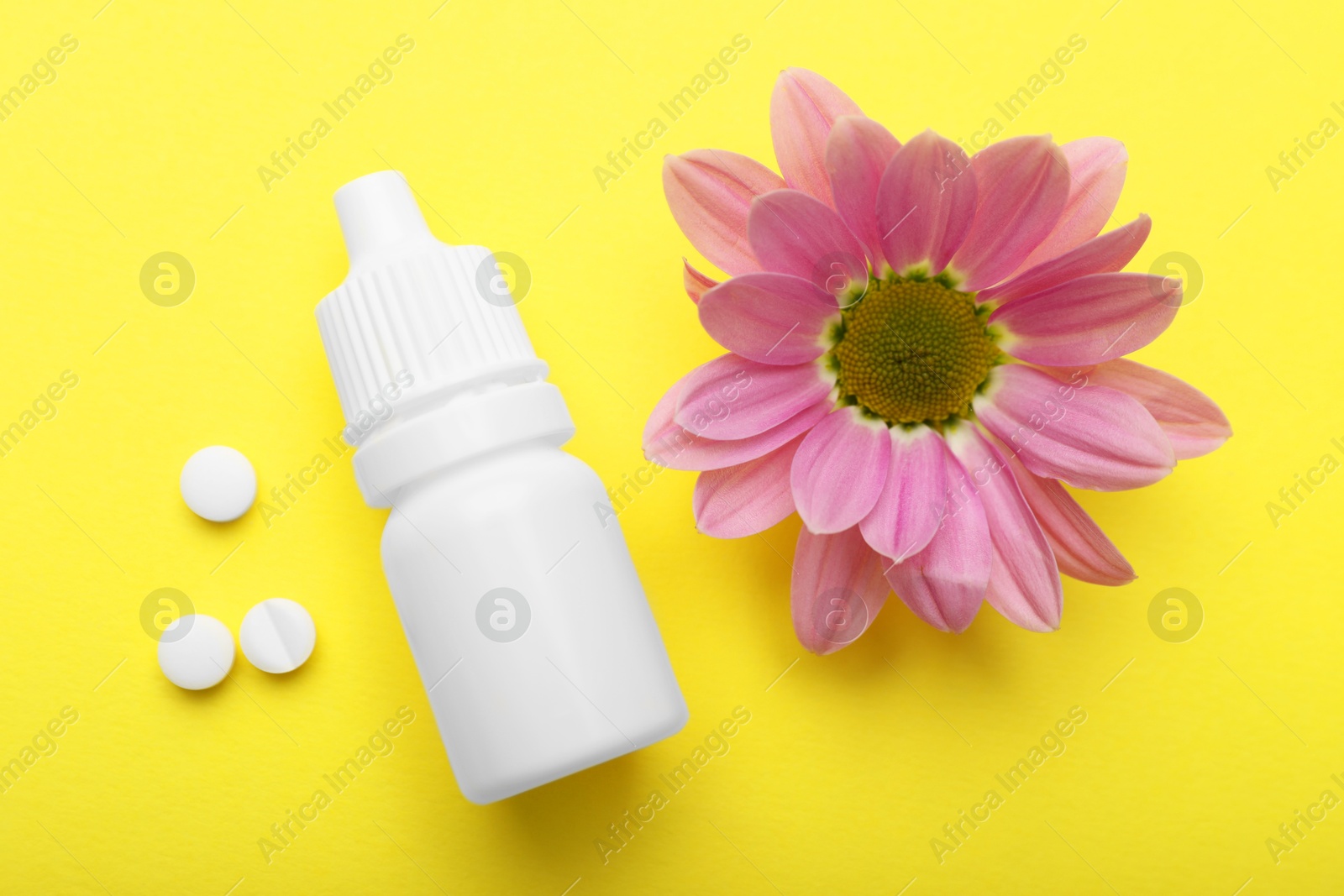 Photo of Allergy treatment. Nasal drops, pills and flower on yellow background, flat lay