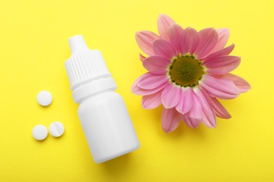 Photo of Allergy treatment. Nasal drops, pills and flower on yellow background, flat lay