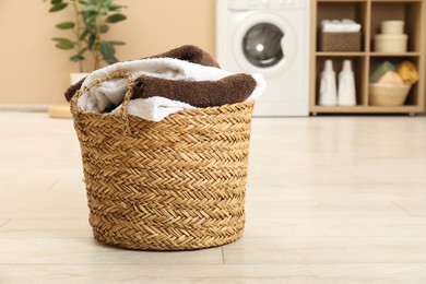 Photo of Wicker basket full of laundry in bathroom