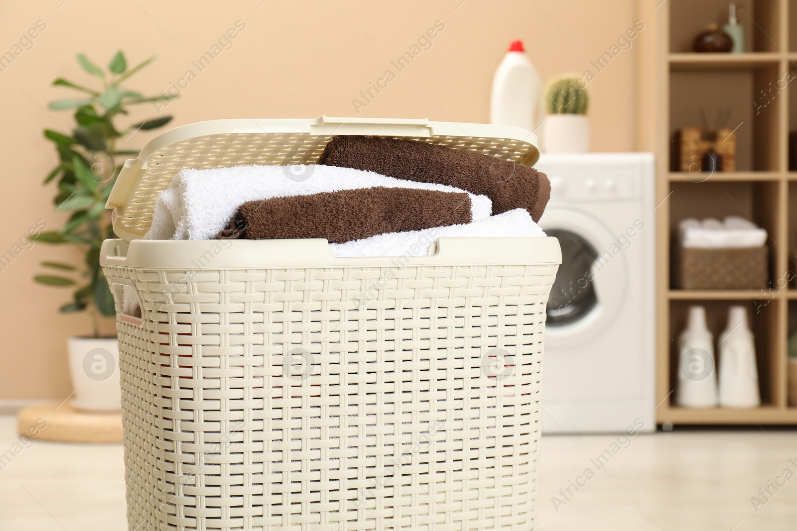 Photo of Wicker basket full of laundry in bathroom