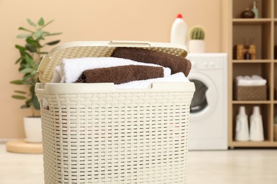 Photo of Wicker basket full of laundry in bathroom