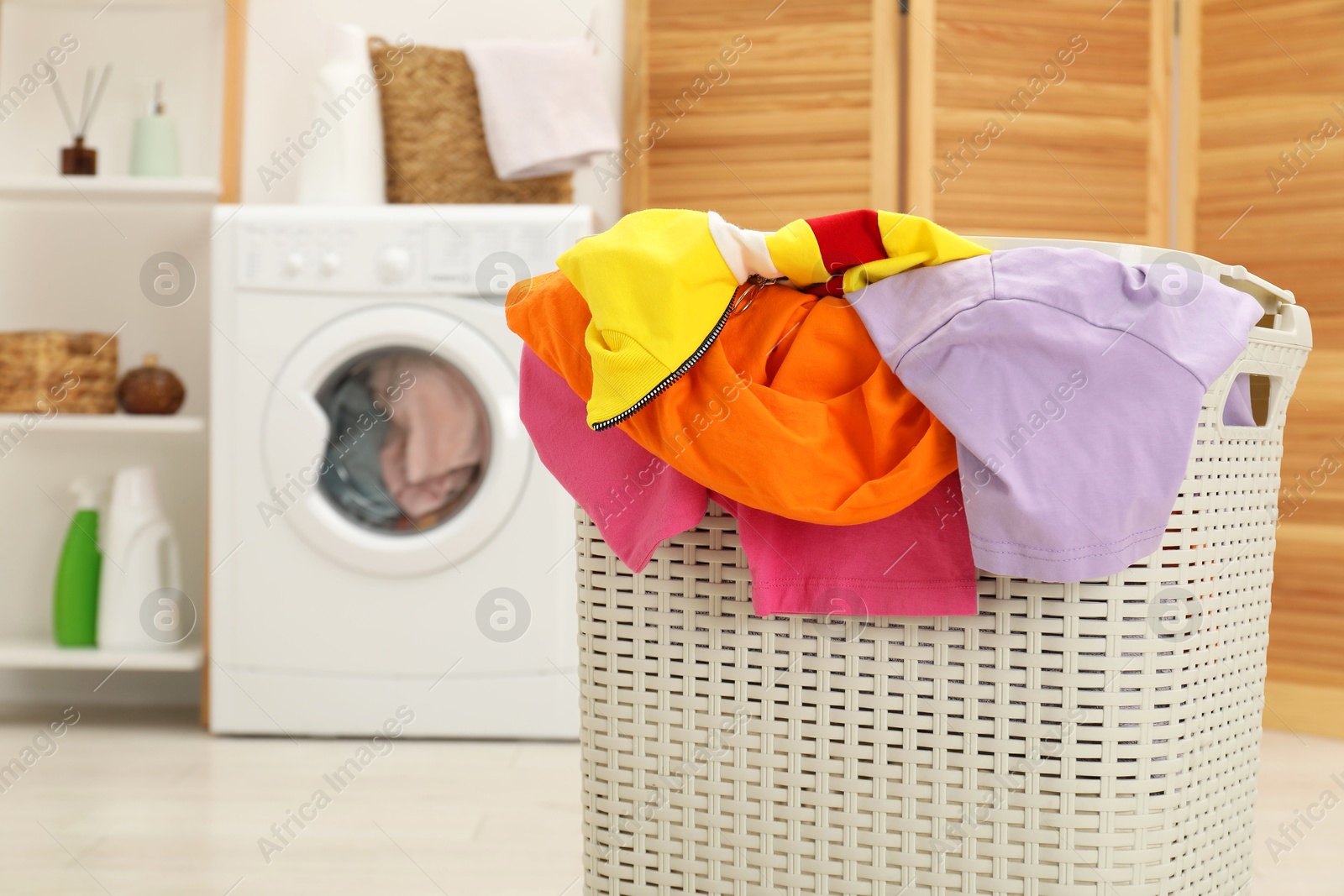 Photo of Wicker basket full of laundry in bathroom