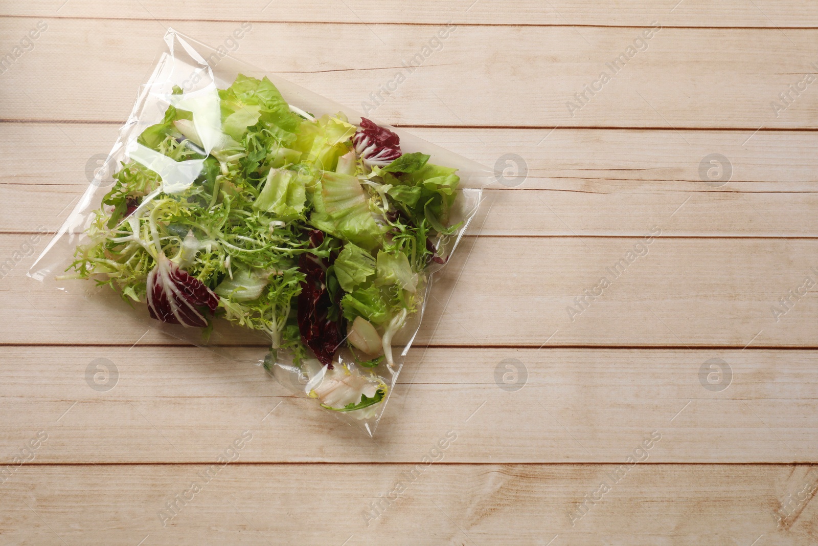 Photo of Pack of fresh salad mix on white wooden table, top view. Space for text