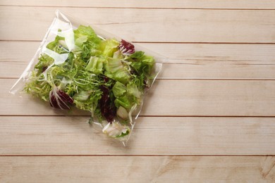 Photo of Pack of fresh salad mix on white wooden table, top view. Space for text