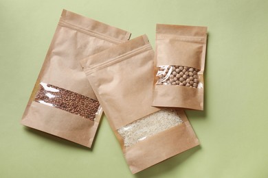 Photo of Paper pouch bags with different products on green background, top view