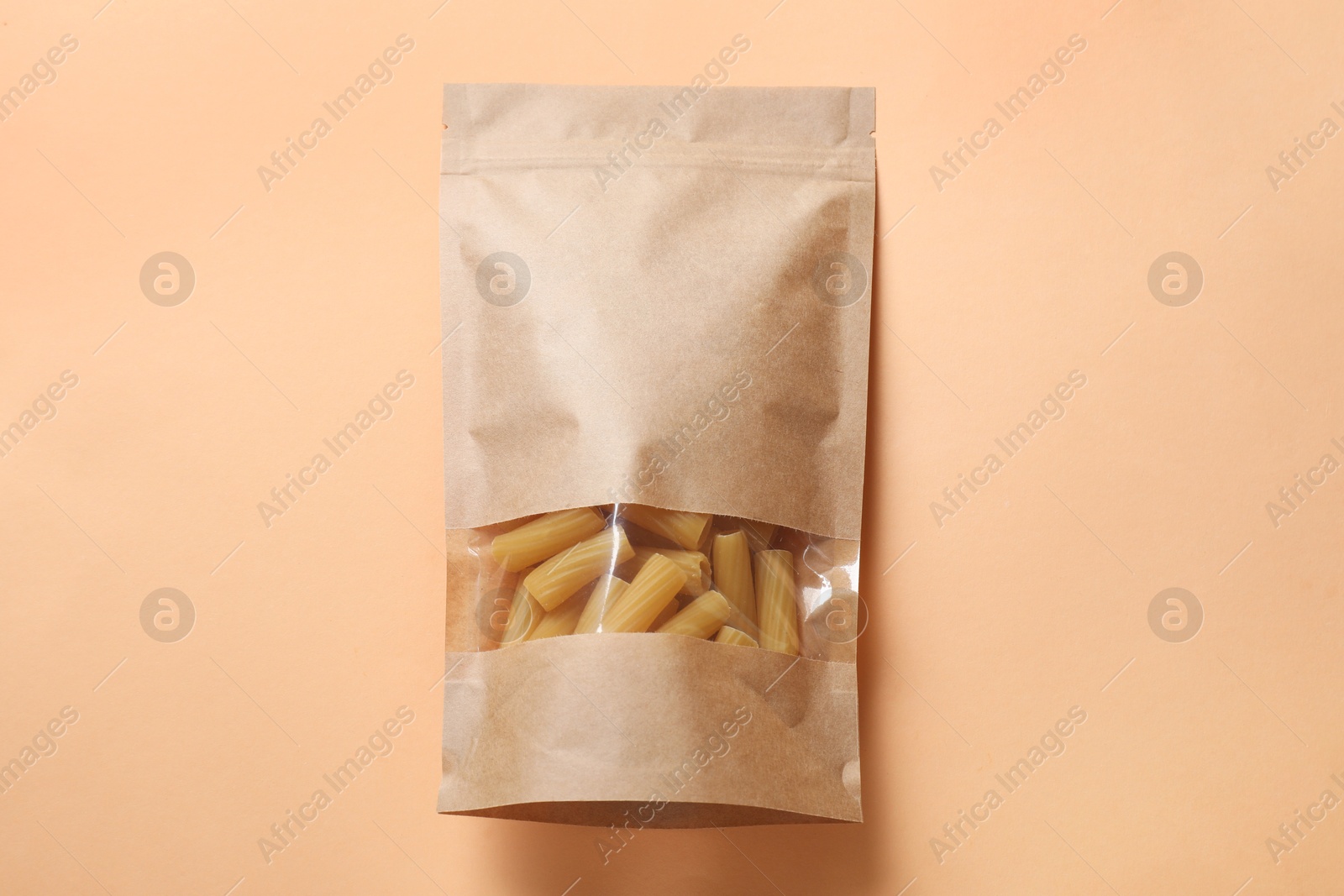 Photo of Paper pouch bag with pasta on color background, top view