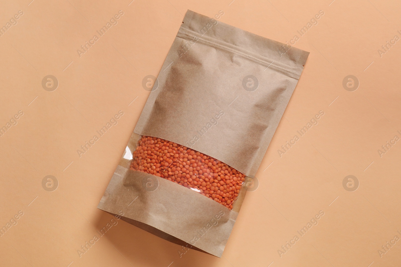 Photo of Paper pouch bag with lentil on color background, top view