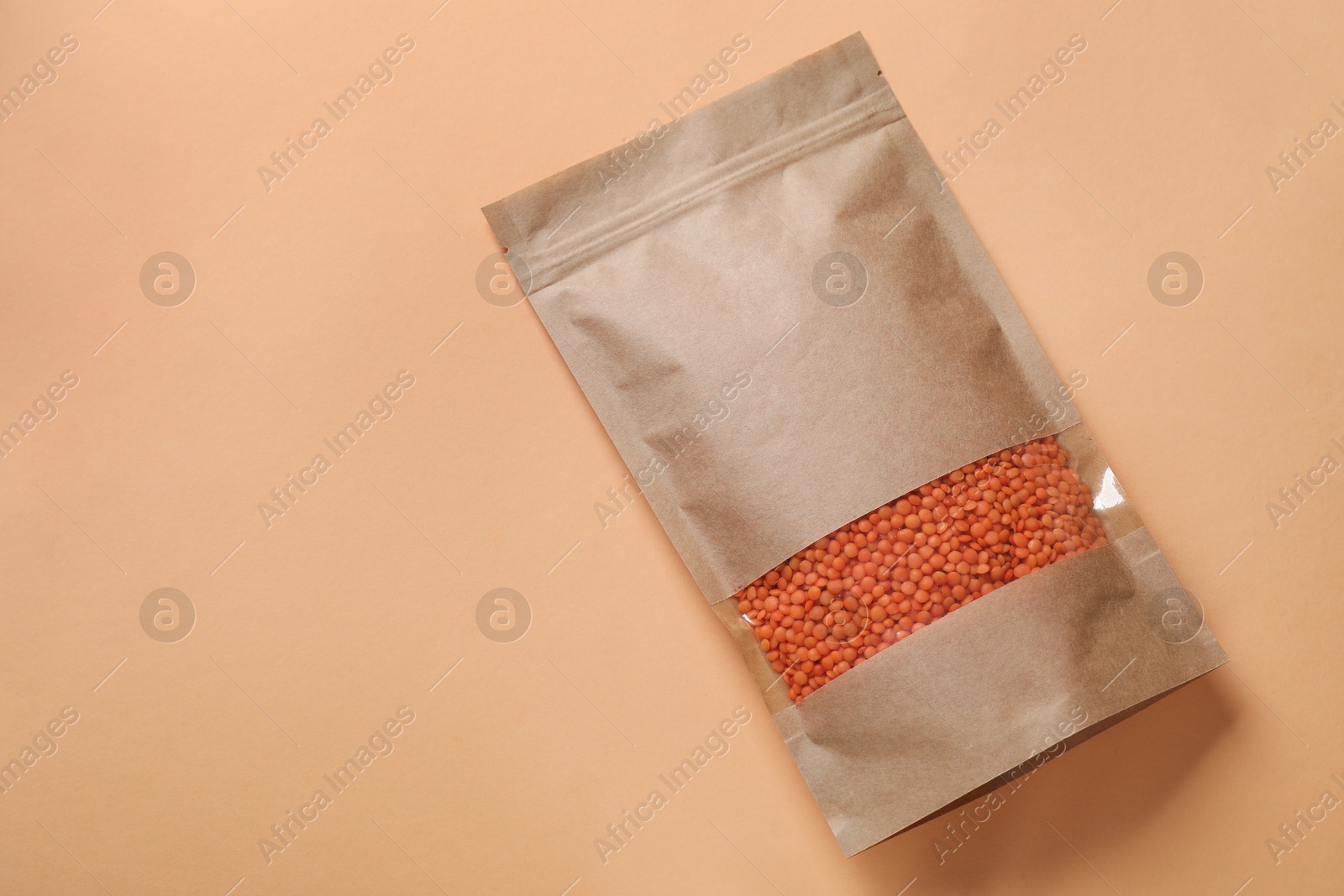 Photo of Paper pouch bag with lentil on color background, top view. Space for text