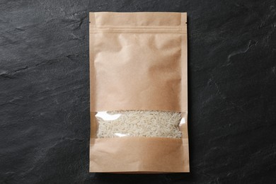 Photo of Paper pouch bag with rice on black table, top view