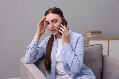 Photo of Stressed woman calling hotline for mental health help in armchair at home