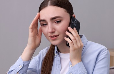 Stressed woman calling hotline for mental health help in armchair at home