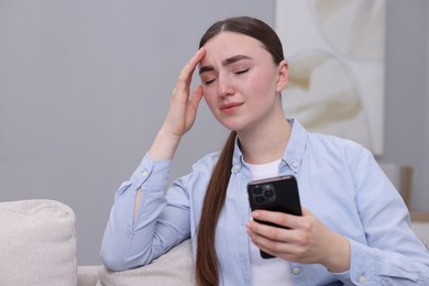 Photo of Depressed woman calling hotline for mental health help on sofa at home. Space for text