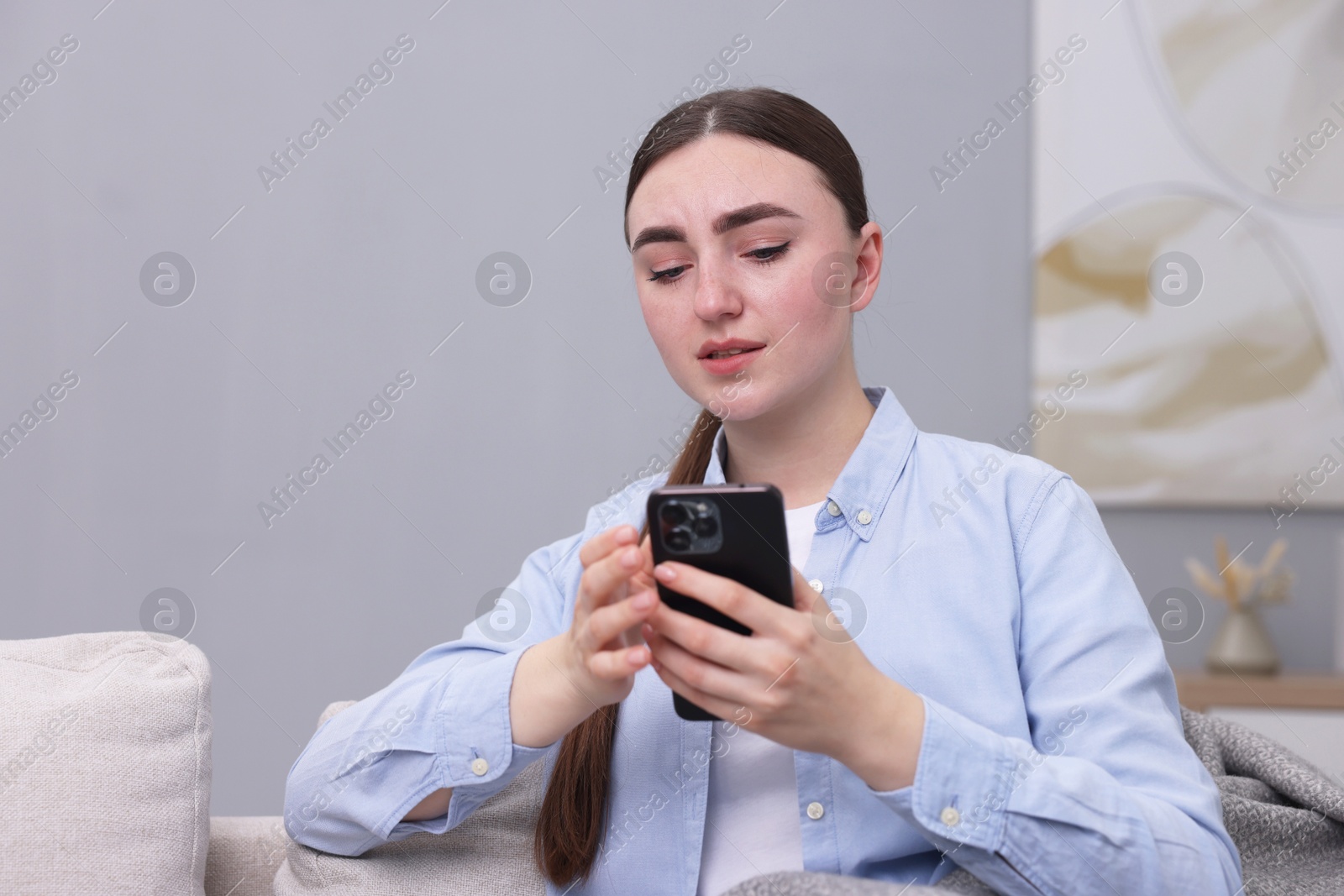 Photo of Depressed woman calling hotline for mental health help on sofa at home. Space for text