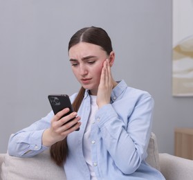 Photo of Depressed woman calling hotline for mental health help on sofa at home. Space for text