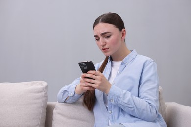 Photo of Depressed woman calling hotline for mental health help on sofa at home. Space for text