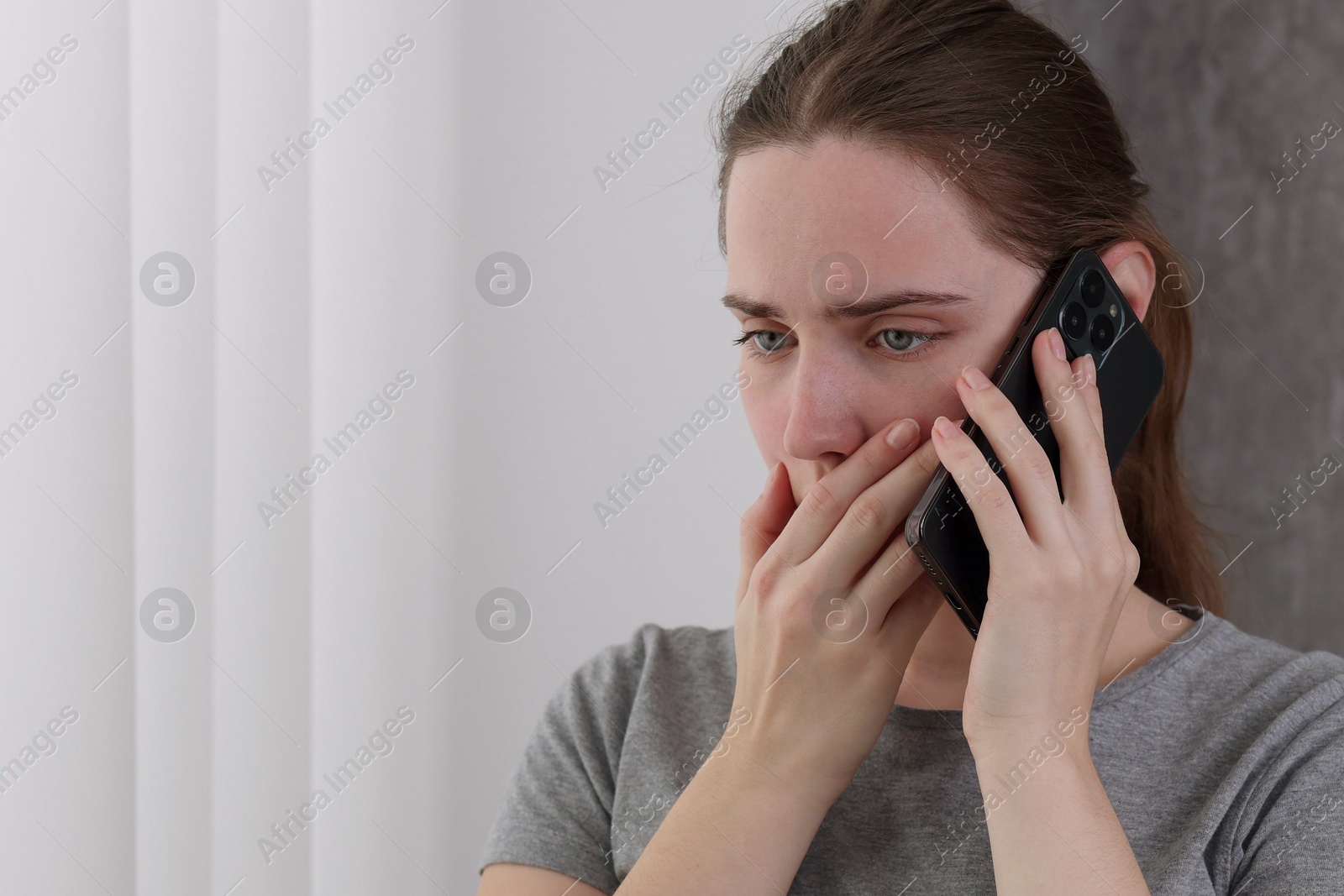 Photo of Stressed woman calling hotline for mental health help near window at home. Space for text