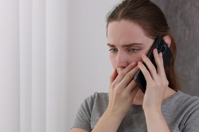 Photo of Stressed woman calling hotline for mental health help near window at home. Space for text