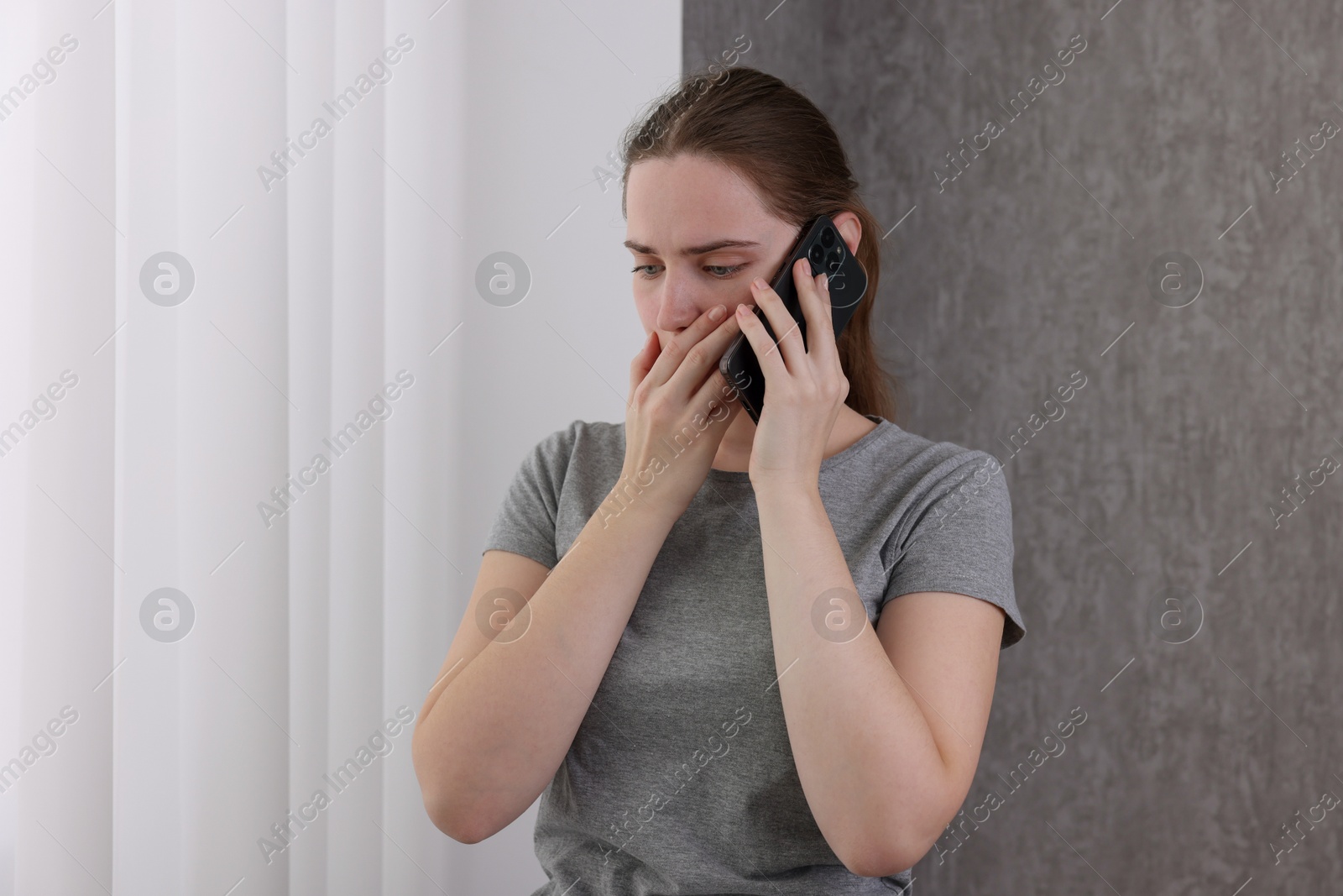 Photo of Stressed woman calling hotline for mental health help near window at home. Space for text