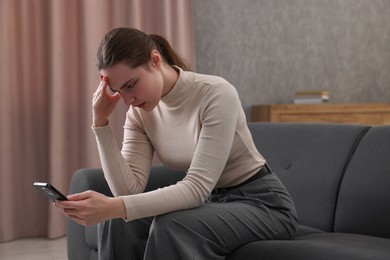 Photo of Depressed woman calling hotline for mental health help on sofa at home