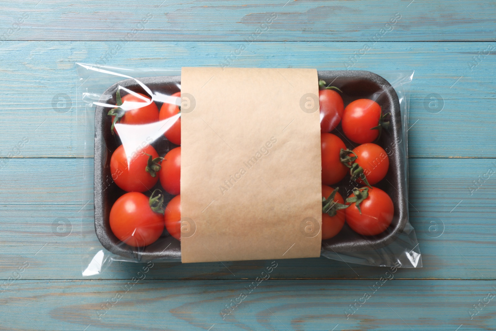 Photo of Pack of fresh tomatoes on light blue wooden table, top view