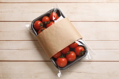 Photo of Pack of fresh tomatoes on wooden table, top view