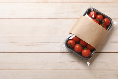 Photo of Pack of fresh tomatoes on wooden table, top view. Space for text