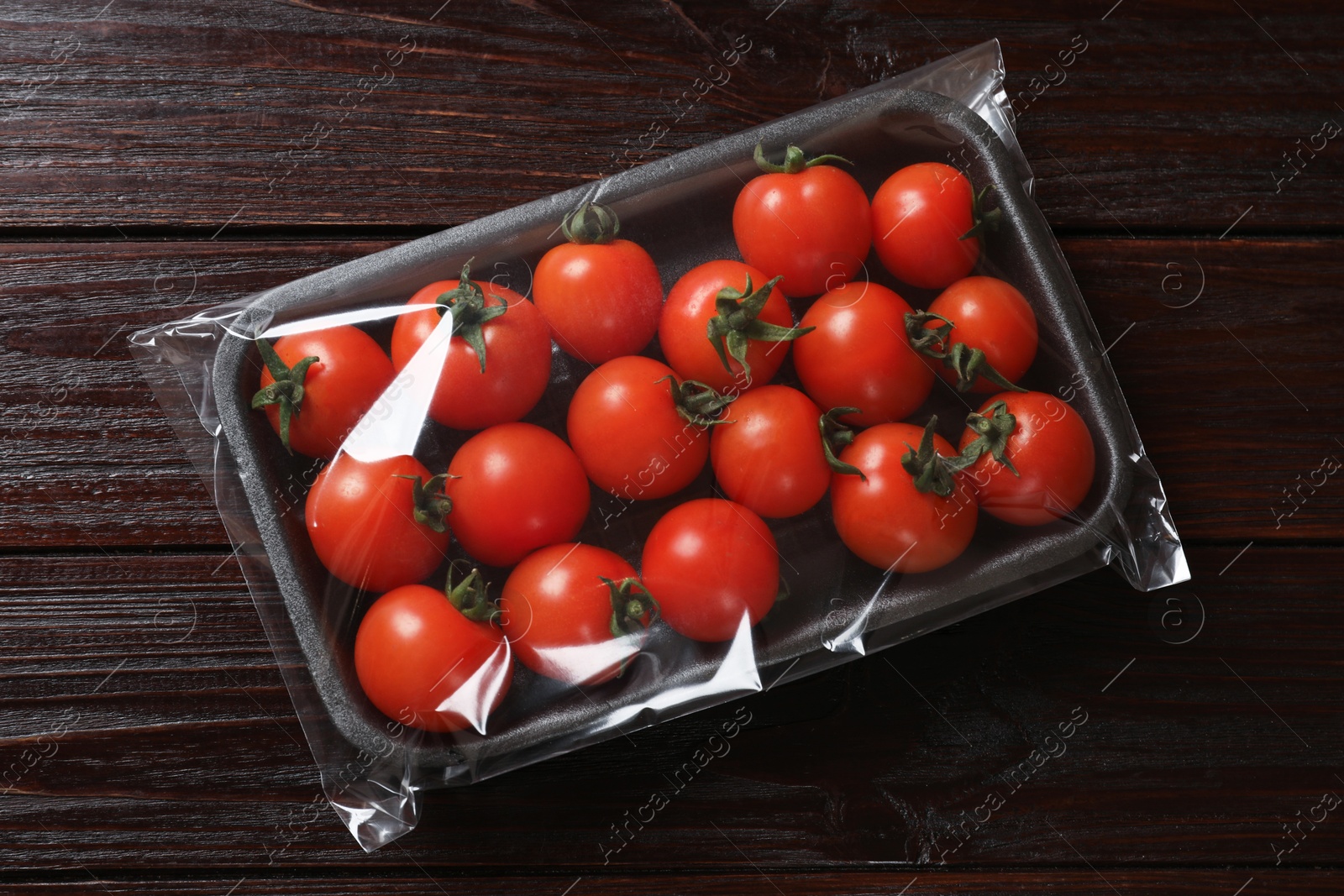 Photo of Pack of fresh tomatoes on wooden table, top view