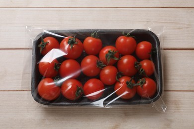 Photo of Pack of fresh tomatoes on wooden table, top view