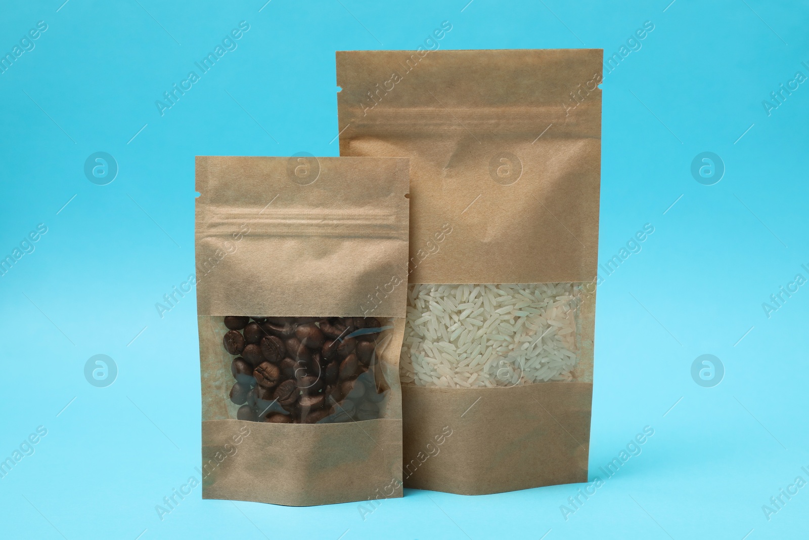 Photo of Paper pouch bags with coffee beans and rice on light blue background