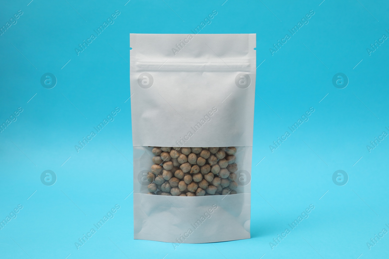 Photo of Paper pouch bag with chickpeas on light blue background