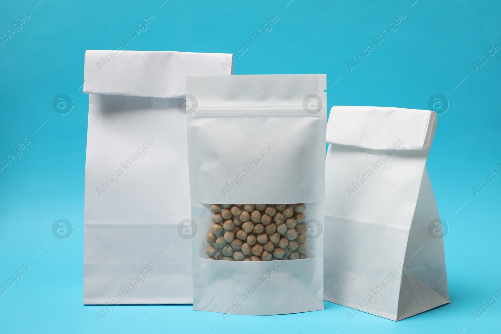 Photo of Paper pouch bag with chickpeas and packs on light blue background