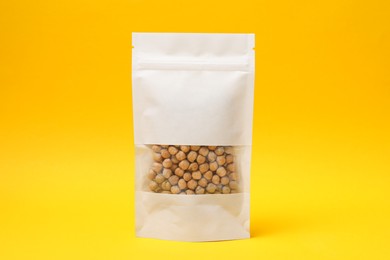 Photo of Paper pouch bag with chickpeas on yellow background