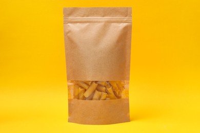 Photo of Paper pouch bag with pasta on yellow background