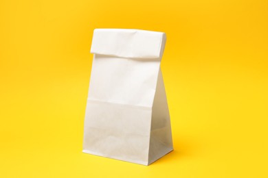 Photo of One closed paper bag on yellow background