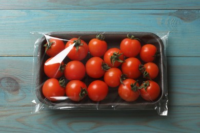 Photo of Pack of fresh tomatoes on light blue wooden table, top view