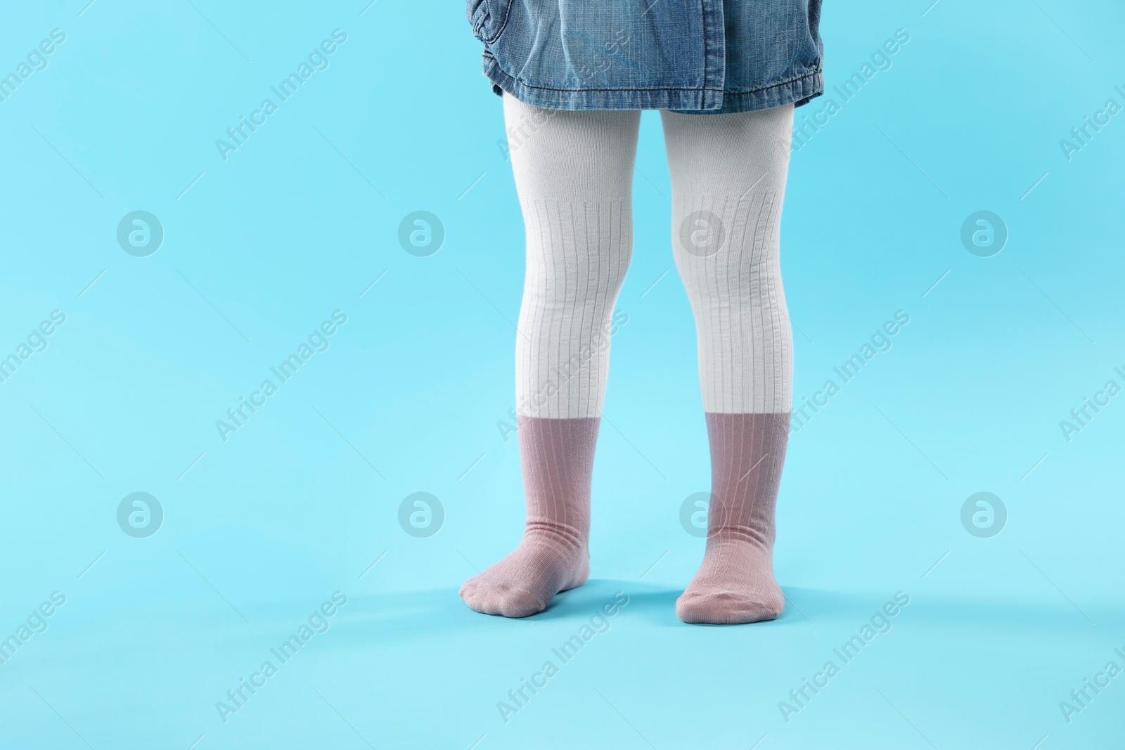 Photo of Child wearing tights on light blue background, closeup. Space for text